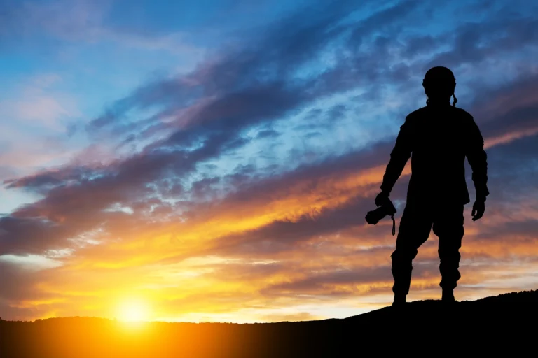 Silhouette eines Fotografen mit Kamera im Gegenlicht bei Sonnenuntergang vor dramatischem, farbintensivem Himmel