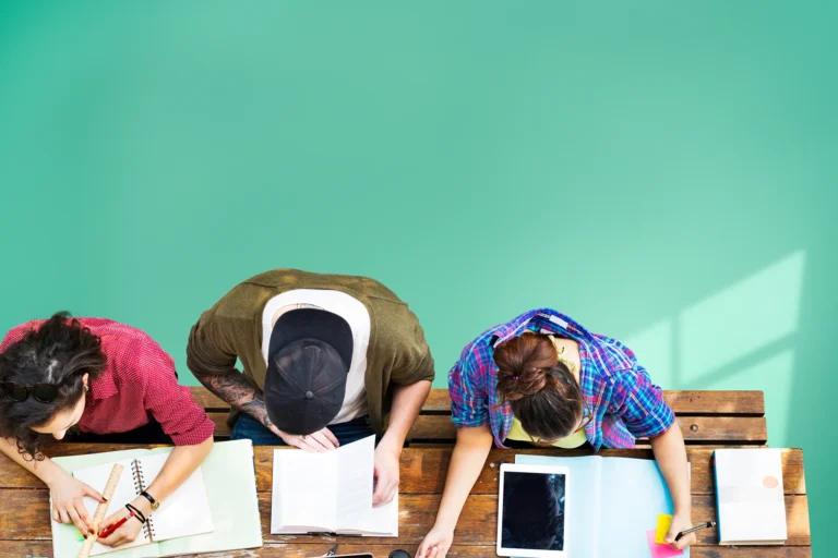 Drei Studierende arbeiten gemeinsam am Tisch während eines Fotografie-Lehrgangs